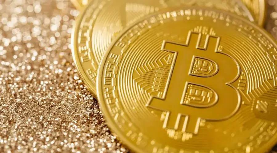Golden Bitcoin coins on a shimmering glitter surface, symbolizing digital currency and financial innovation.