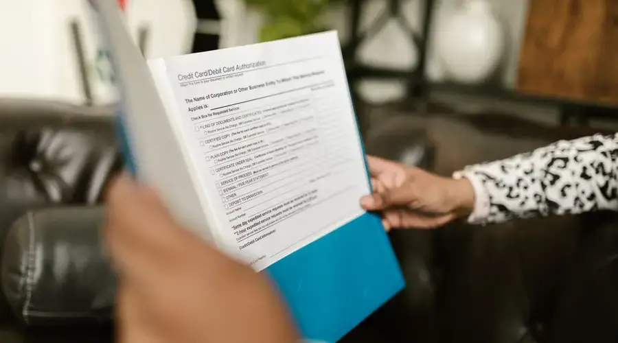 Close-up of a person examining a credit card authorization form inside an office setting.