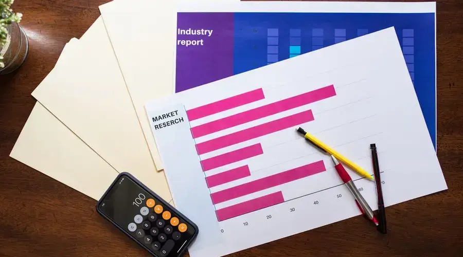 Top view of market research reports and calculator on a wooden desk, illustrating business analysis.