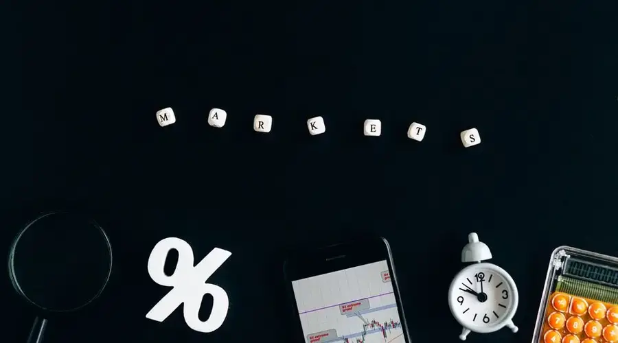 Creative arrangement depicting financial markets with cubes, graphs, and a clock on a black background.