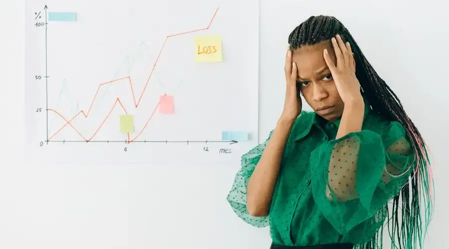 Businesswoman analyzing financial chart with loss noted, expressing stress.