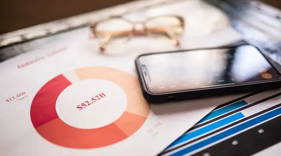 A mobile phone over business charts displaying financial data for analysis.