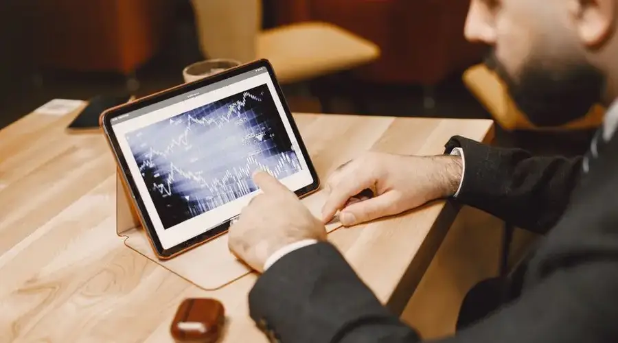 Business professional reviewing stock market data on a tablet in a modern office setting.