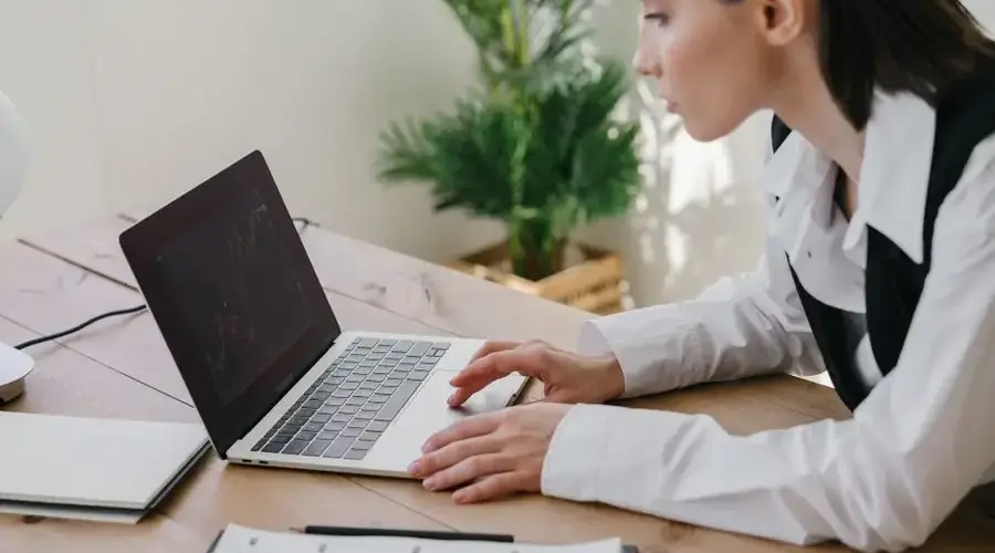 Businesswoman working on stock market graphs in modern office setting with laptop and charts.