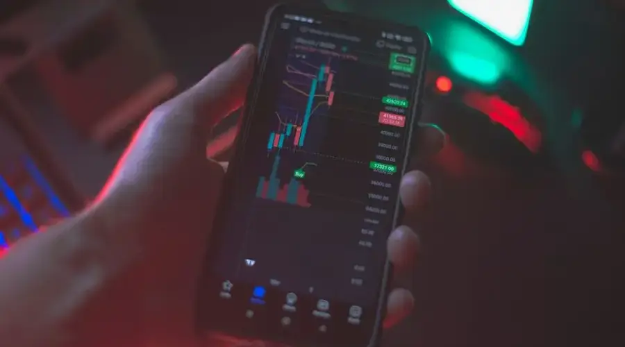 Hand holding smartphone displaying cryptocurrency trading app with financial data.
