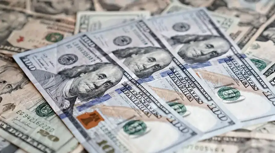 A detailed close-up of multiple U.S. dollar banknotes arranged in a scattered layout.