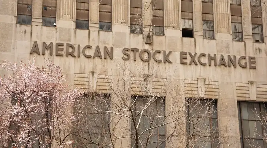 Facade of the American Stock Exchange Building in New York City during spring with blooming trees.