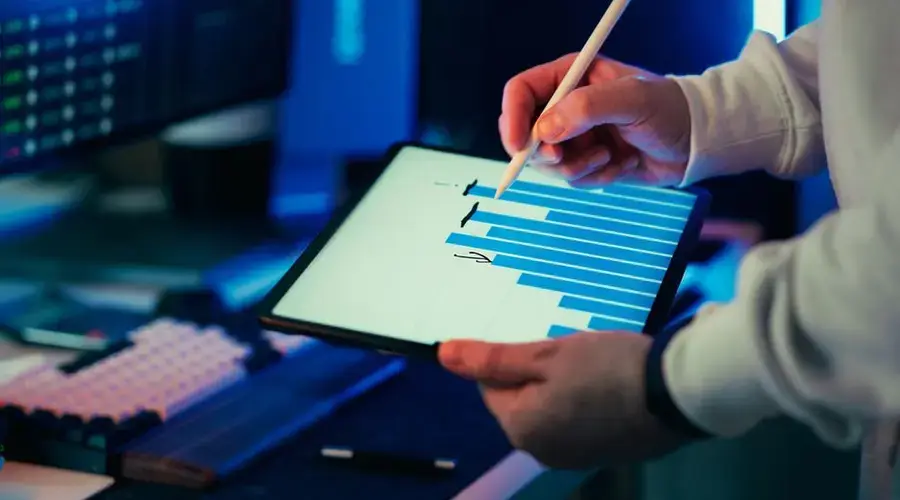 A person using a stylus on a tablet showing a business graph in an office setting.