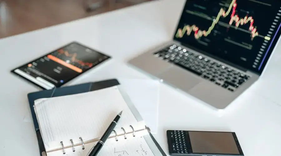 A modern workspace featuring a laptop with charts, notebook, and gadgets for productivity.