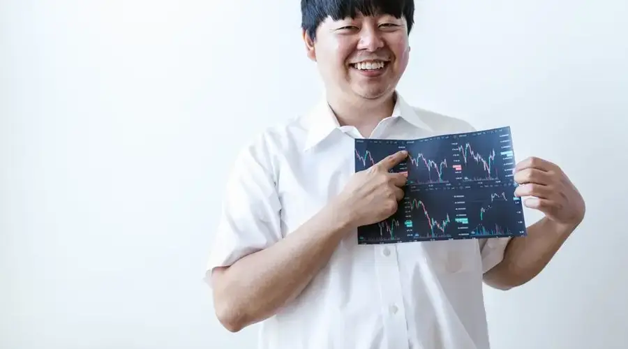 Smiling man presenting cryptocurrency investment chart indoors.