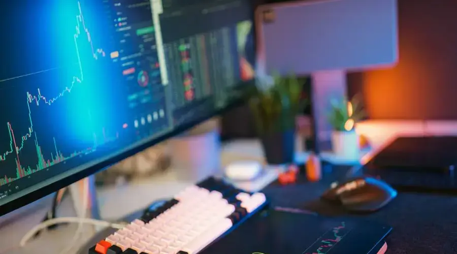 Modern workspace with screens displaying cryptocurrency market data and trends.
