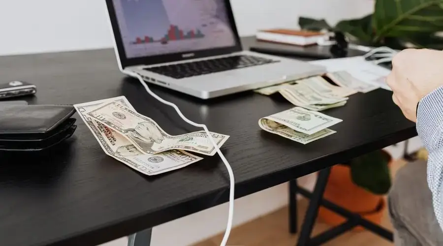 A workspace with cash, laptop, and financial graph showing investment analysis.
