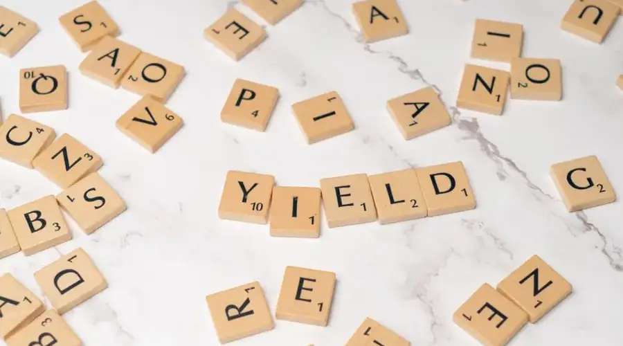 Scrabble tiles forming the word 'YIELD' on a marble surface, symbolizing finance and investment.