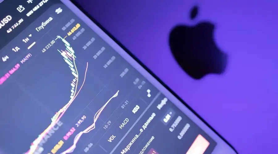 Close-up of a stock market graph on a digital device with an Apple logo in purple lighting.