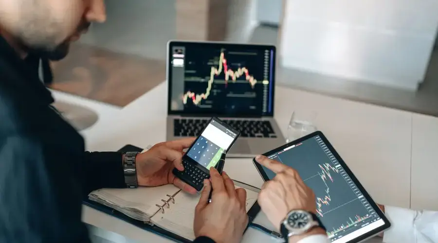 Two professionals examining financial data on digital devices at a modern office.