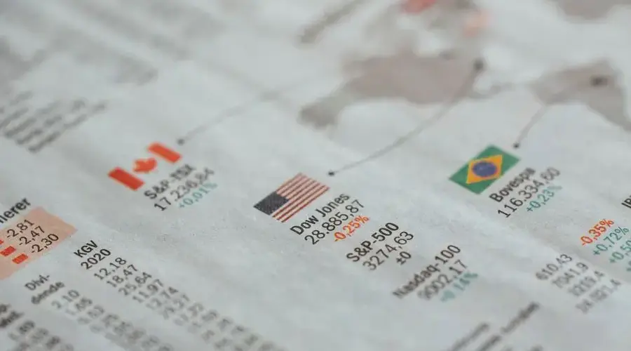 Detailed close-up of a newspaper displaying global financial market statistics and country flags.