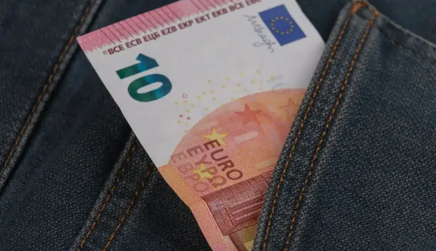 Close-up of a 10 euro banknote sticking out from a denim pocket.