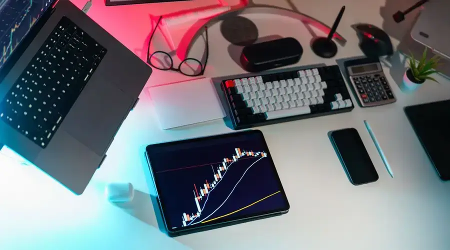 A modern desk setup featuring financial analytics on digital devices in an office setting.