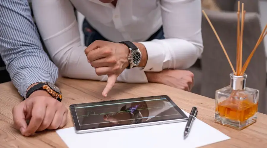 Two business professionals discussing a graph on a digital tablet over a wooden table.