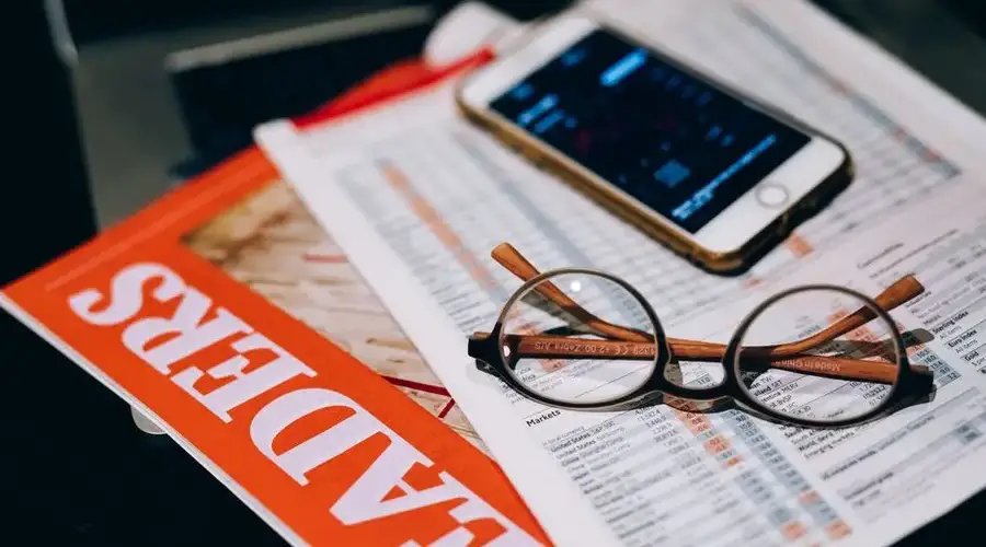 A close-up of business analytics tools including a smartphone, eyeglasses, and papers.
