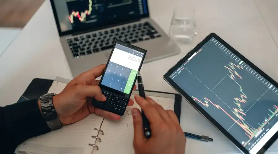 A workspace with devices, charts, and a calculator used for trading analysis.