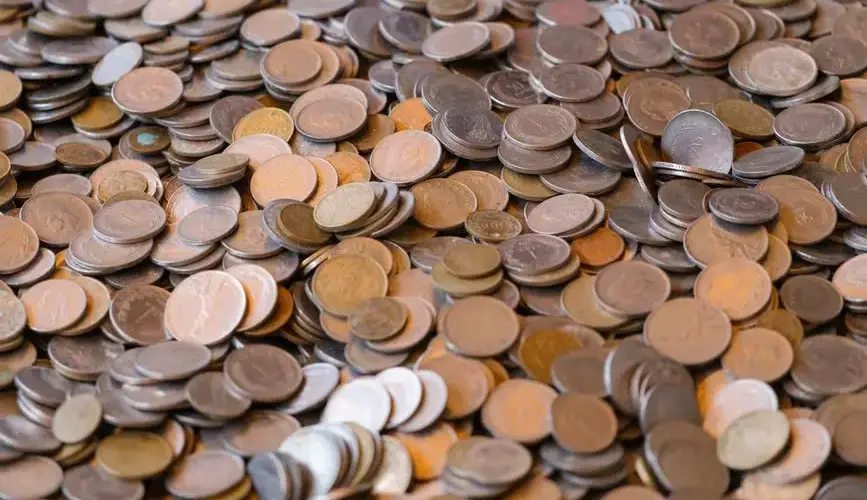 A large pile of mixed coins representing wealth and financial concepts.