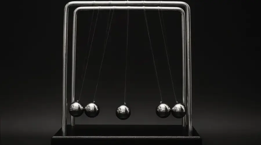 Newton's cradle for physics principles and motion study on a dark background.