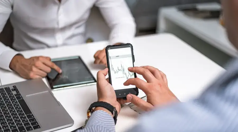 Two business professionals analyzing market trends on digital devices in an office setting.