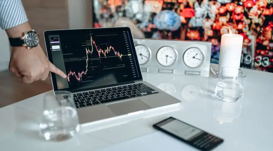 Businessman pointing at a financial graph on a laptop screen, showcasing stock market analysis.