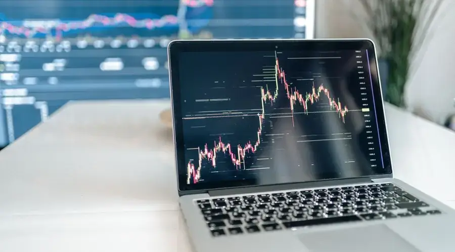A laptop on a desk showing detailed cryptocurrency graphs for data analysis.
