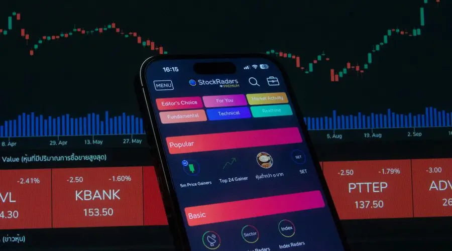 Close-up of a smartphone displaying a stock trading app against a backdrop of market charts.