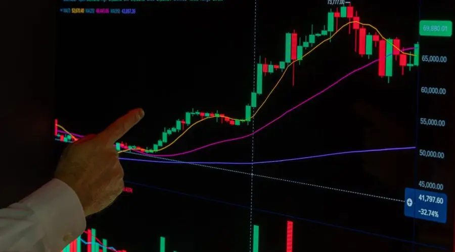 Hand pointing at cryptocurrency chart showing market trends and analysis.