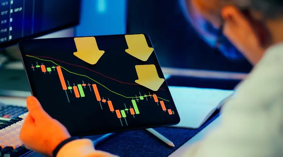 A businessman analyzing a bearish stock market trend on a tablet, indicating financial instability and potential crisis.