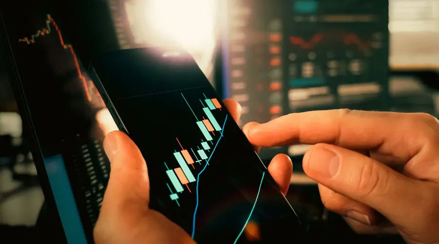 Hands interacting with financial charts on a smartphone, showcasing stock market trends.