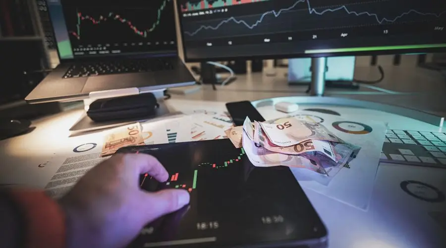 A modern trading desk with screens showing market charts and euro notes, capturing a trading atmosphere.