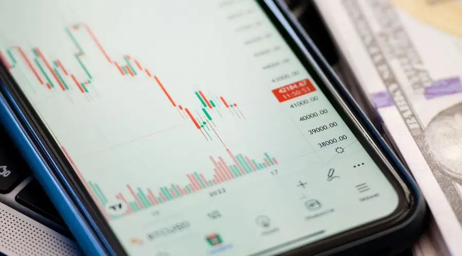 Detailed view of stock market data on a smartphone with US dollars in the background, illustrating trading.