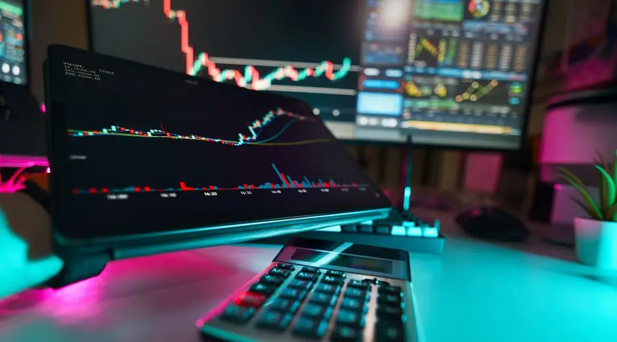 A vibrant office setup with digital tablets displaying financial analysis and stock charts, complemented by a calculator.