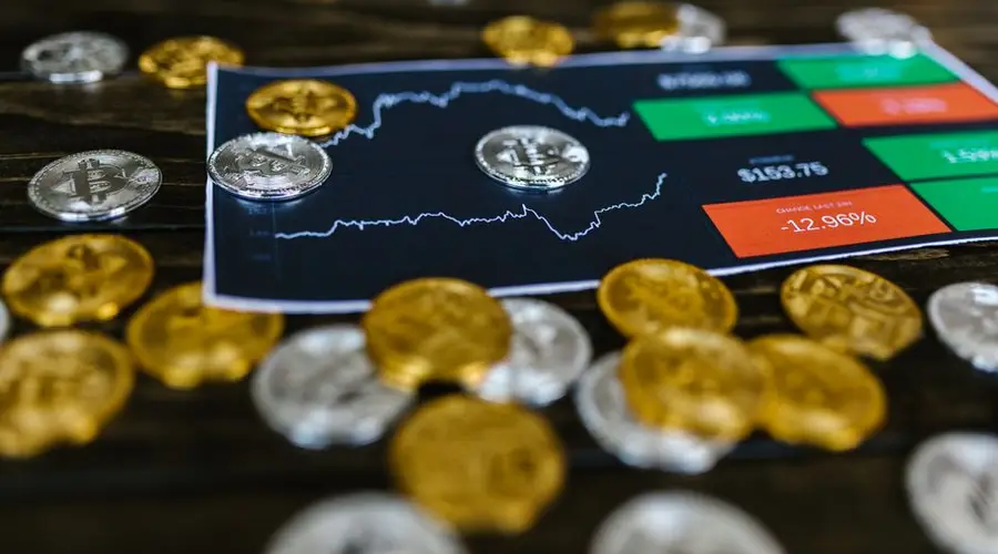 Bitcoin and altcoins on table with digital trading chart indicating market trends and investment details.