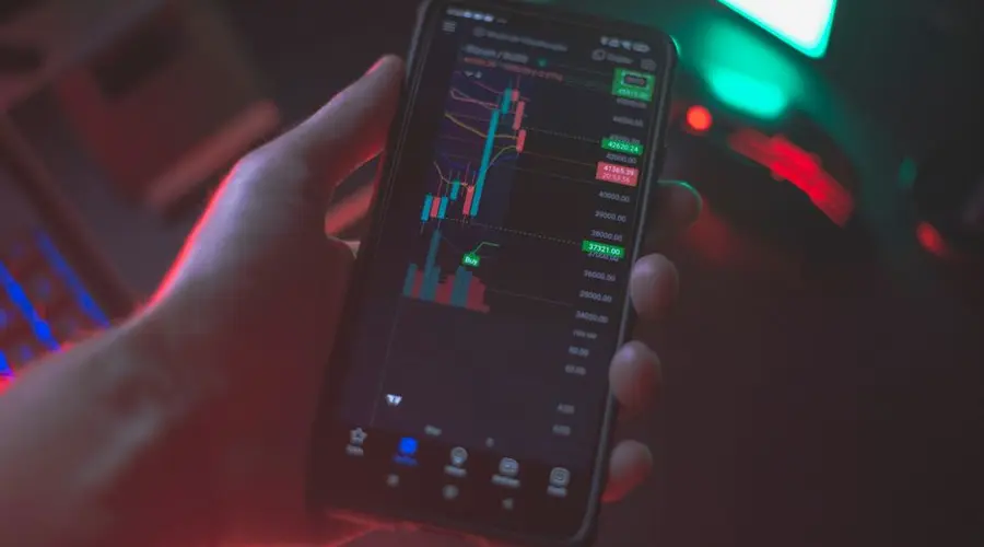 Hand holding smartphone displaying cryptocurrency trading app with financial data.