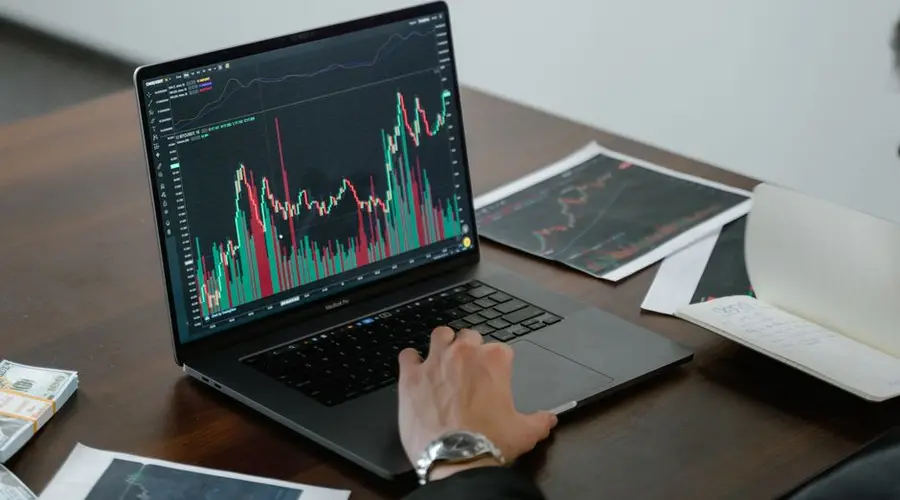 A person analyzing stock market data on a laptop with charts and graphs visible.