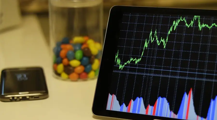 Tablet display of stock market data with smartphone and colorful candies on desk.