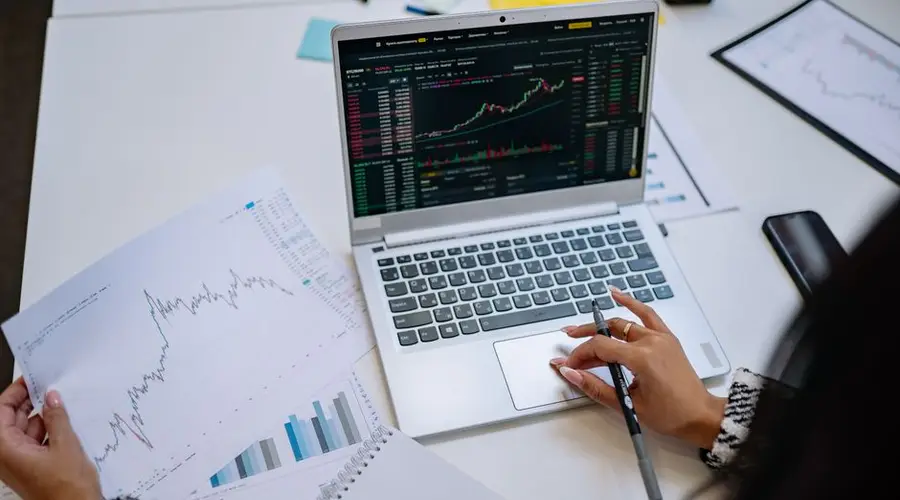 A detailed look at business analysis with a laptop displaying graphs and financial charts on a table.