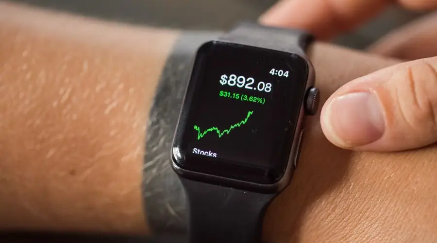 Close-up of a smartwatch showing stock market trends and financial data.