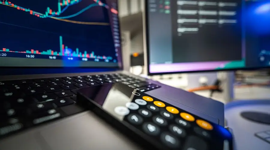 Close-up view of financial analysis on laptop and screen with calculator for business strategy.
