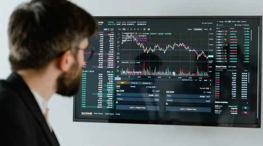 A businessman in a suit looks at a screen displaying stock market charts and data analysis.