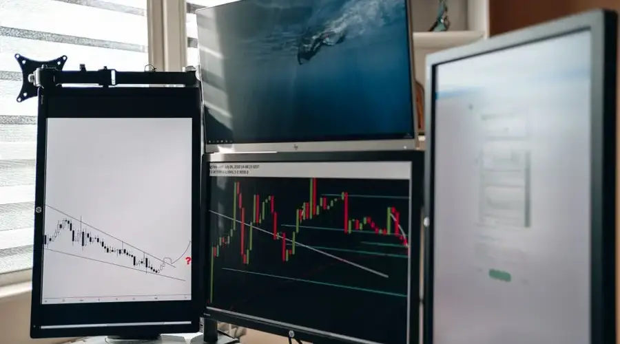 A home office setup featuring multiple monitors displaying trading charts and data analysis.