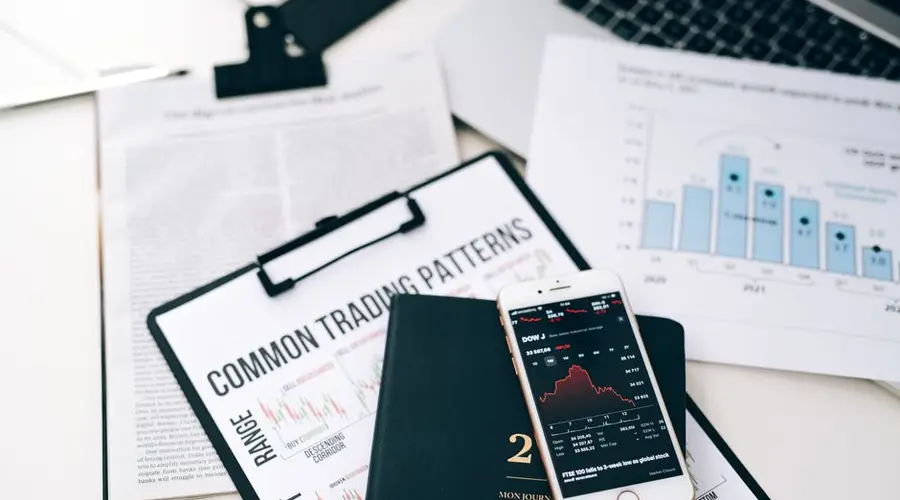 Overhead view of financial graphs and smartphone displaying stock market trends on a desk.
