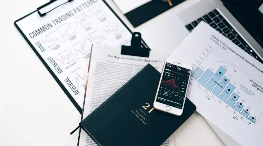 High-angle shot of a stock trading desk with charts, graphs, and a smartphone displaying market trends.