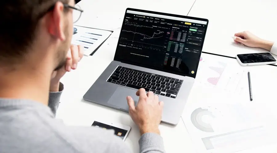 Business professional analyzing stock market data on a laptop for investment insights.