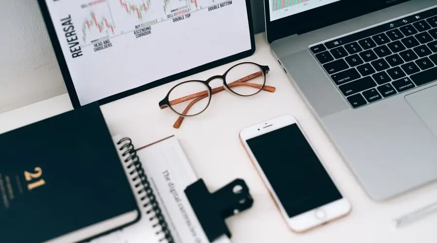 A modern work desk setup featuring electronic devices and financial graphs for productivity.